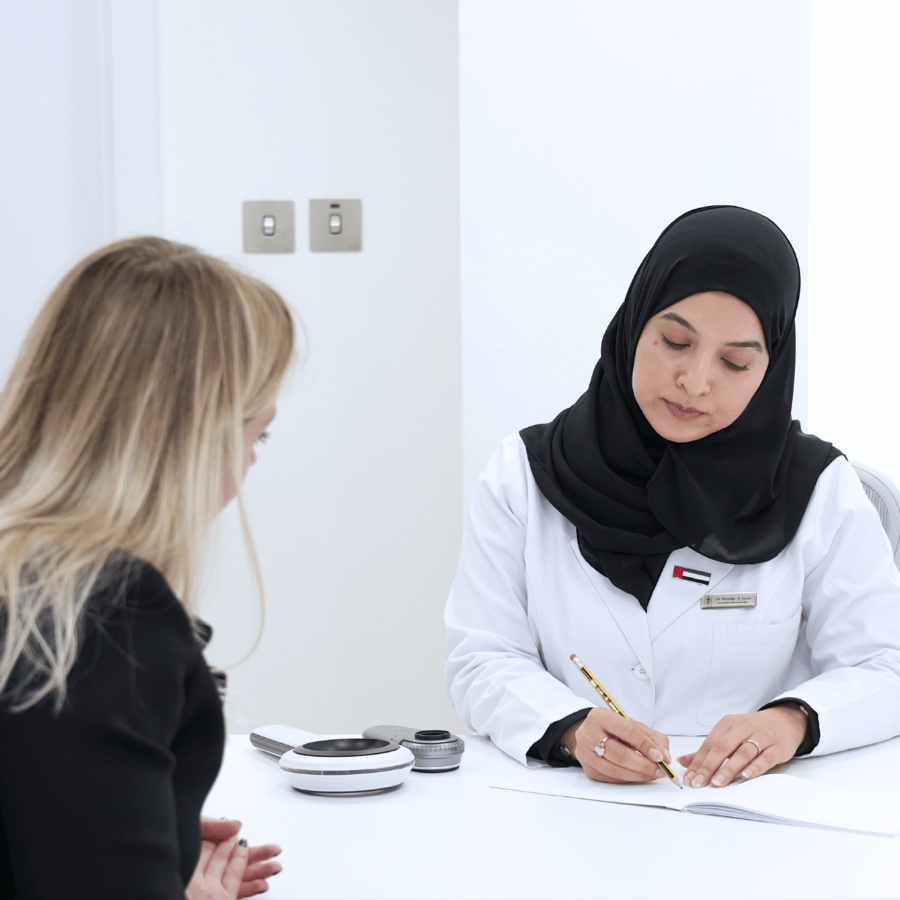Dr. Khadija Al-Zaabi in patient consultation — evidence-based dermatology Abu Dhabi
